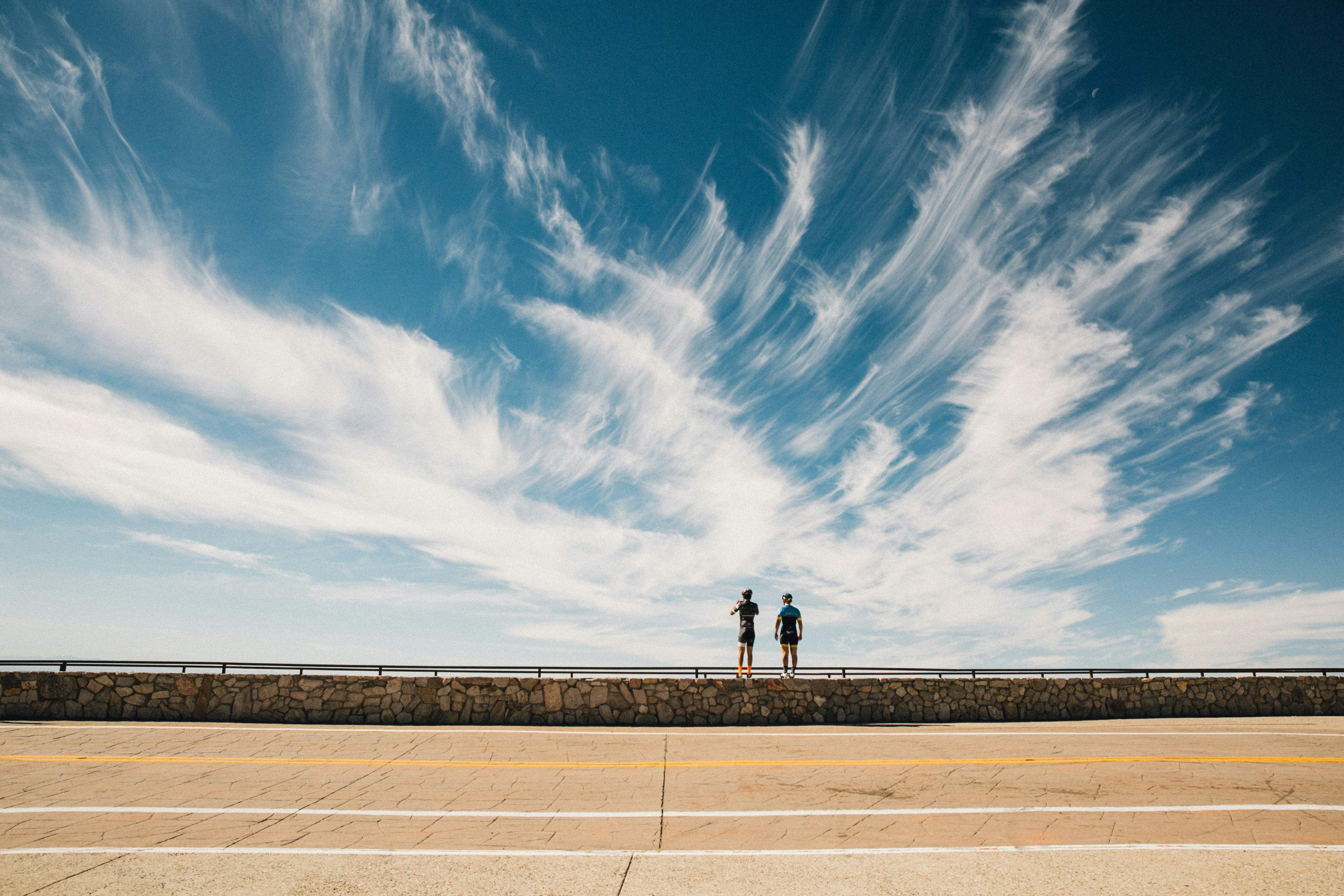 two persons standing on handrail during day